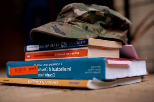 Army hat resting on top of college textbooks